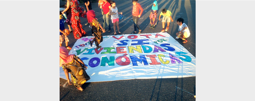 Children standing and playing around a banner placed on the street.