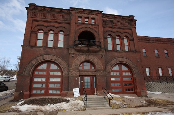 View from street level of Firehouse No. 1, and a portion of its annex behind and to the right of the firehouse. Romanesque features such as intricate brick-work, stone detailing, and arched windows distinguish the National Register buildings.