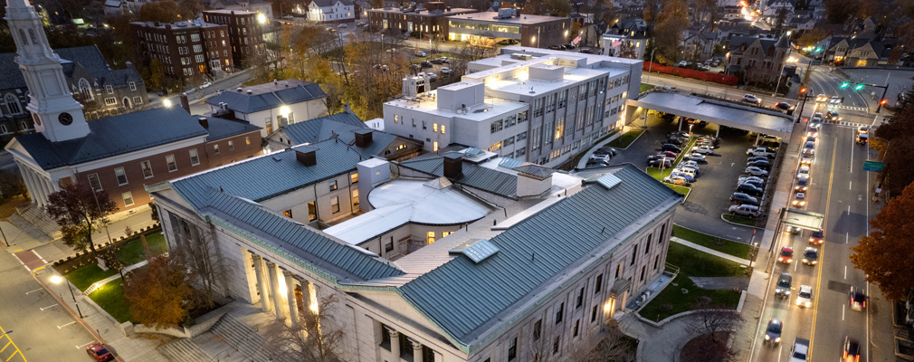 Aerial photograph of the Courthouse Lofts, its principal courthouse building in the foreground and annex building in the background, in the context of the surrounding Lincoln Square neighborhood of Worcester, Massachusetts.