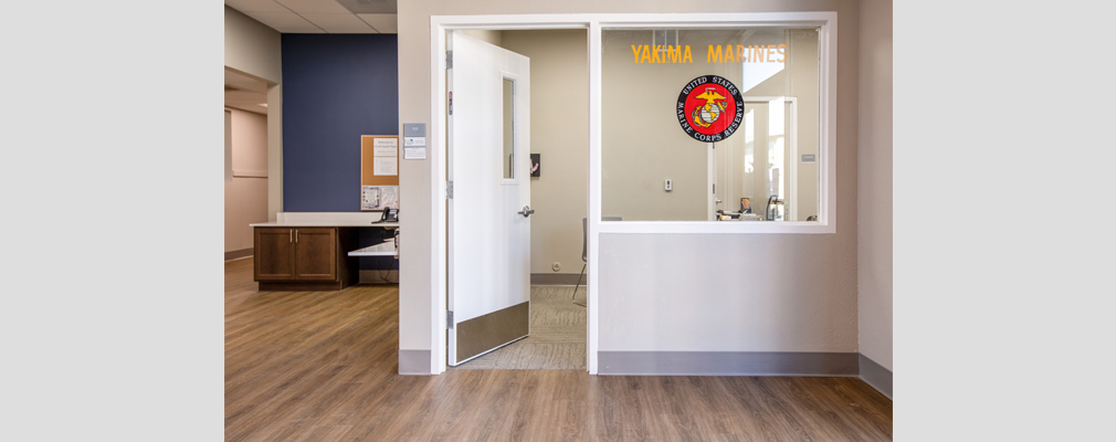 Photograph of the indoor office spaces at Chuck Austin Place with a sign “Yakima Marines” and the insignia of the U.S. Marine Corps on the window glass.
