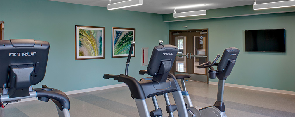 Photograph of a large room with a stationary bike, stair stepper, and treadmill.