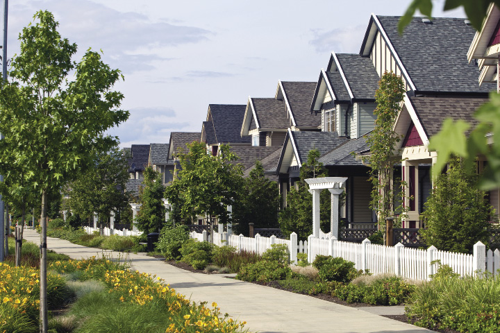 A row of single family homes with white picket fences situated close to each other.