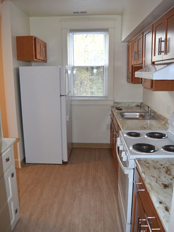 A kitchen room with a fridge, stove, sink, cabinetry, and countertops.