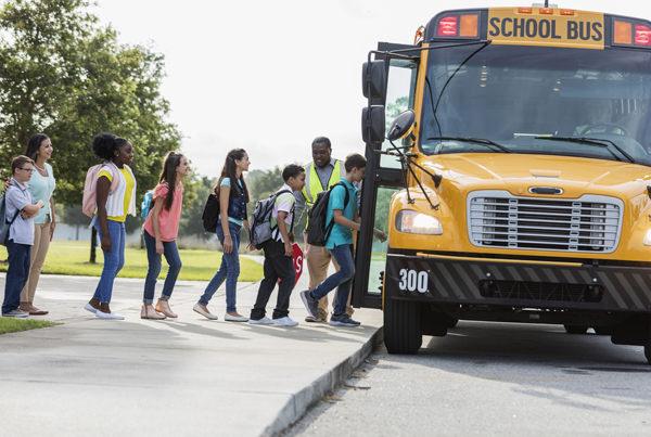 A line of children boarding a school bus.